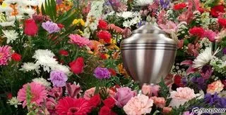 Urne cinéraire en métal argenté entourée d'une composition florale colorée