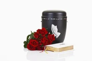 Urne funéraire noire avec mains en prière, roses rouges et livre religieux