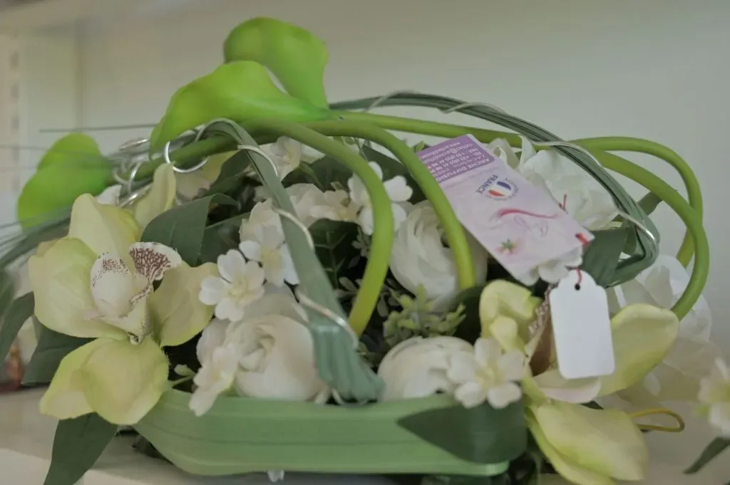 Composition florale artificielle de fleurs blanches et orchidées avec étiquette