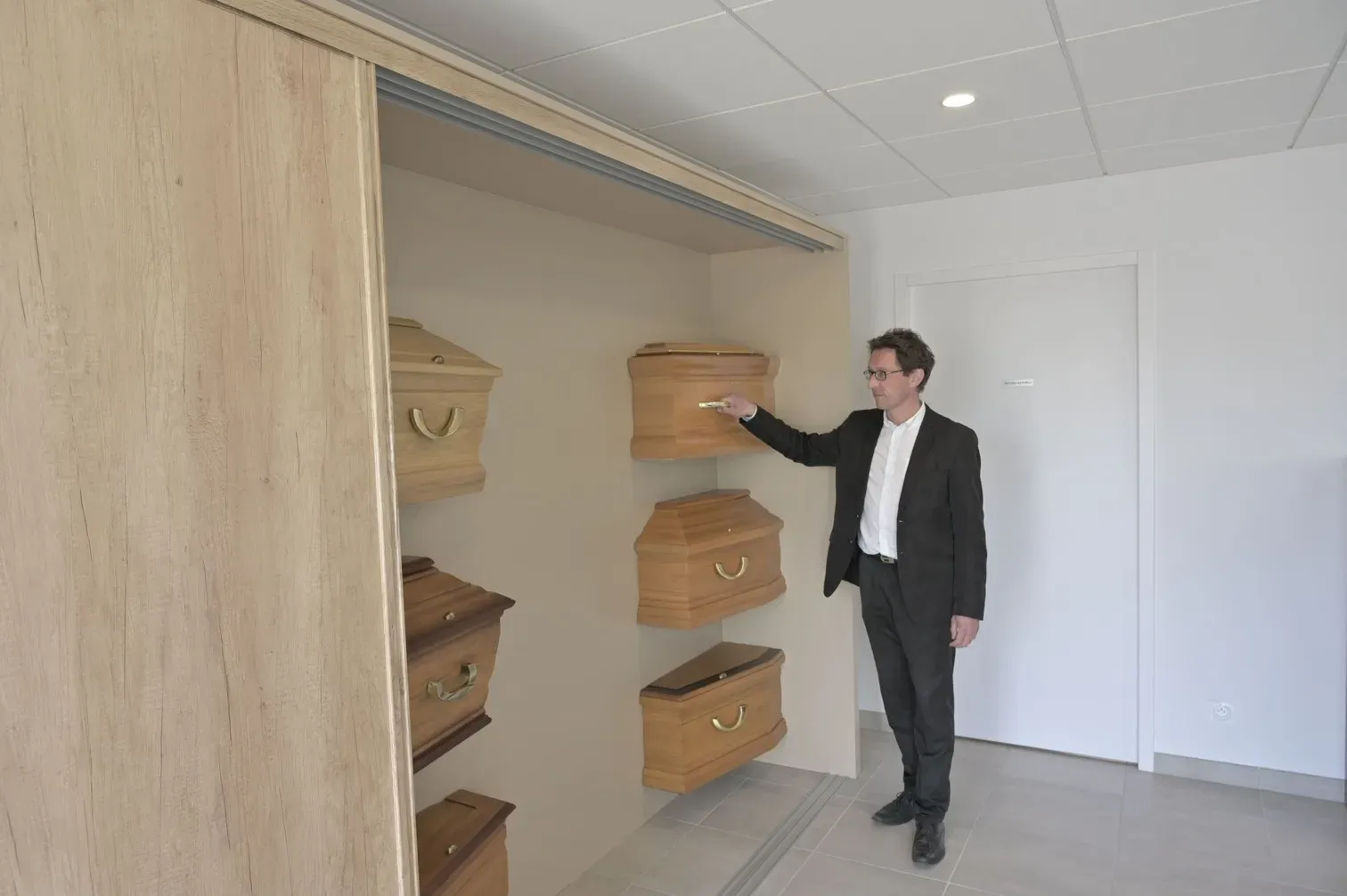 Conseiller funéraire présentant une armoire d'exposition de modèles de cercueils