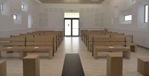 Grande salle de cérémonie funéraire lumineuse avec bancs en bois alignés et allée centrale