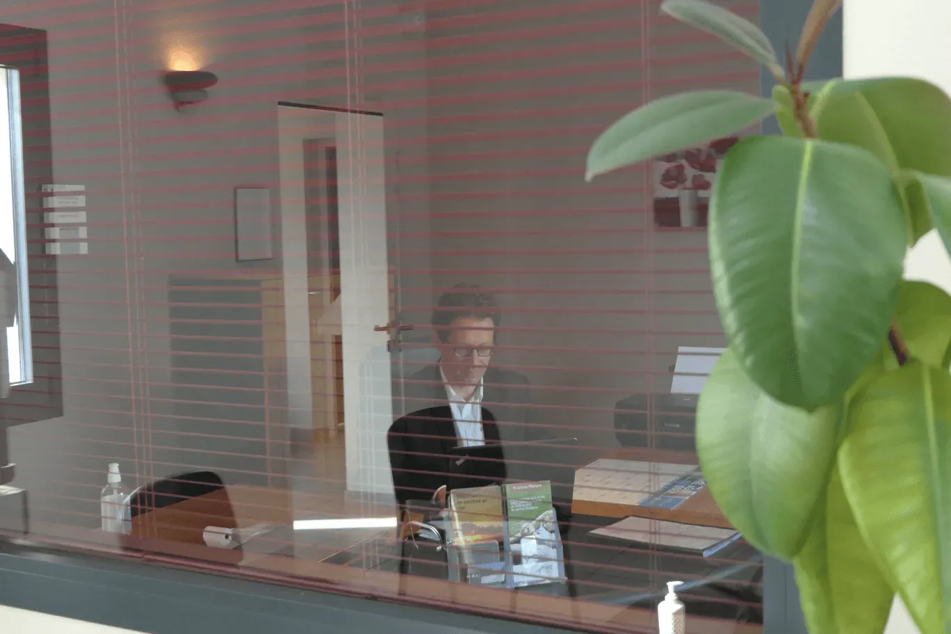 Conseiller funéraire travaillant à son bureau vu à travers la vitre d'une agence